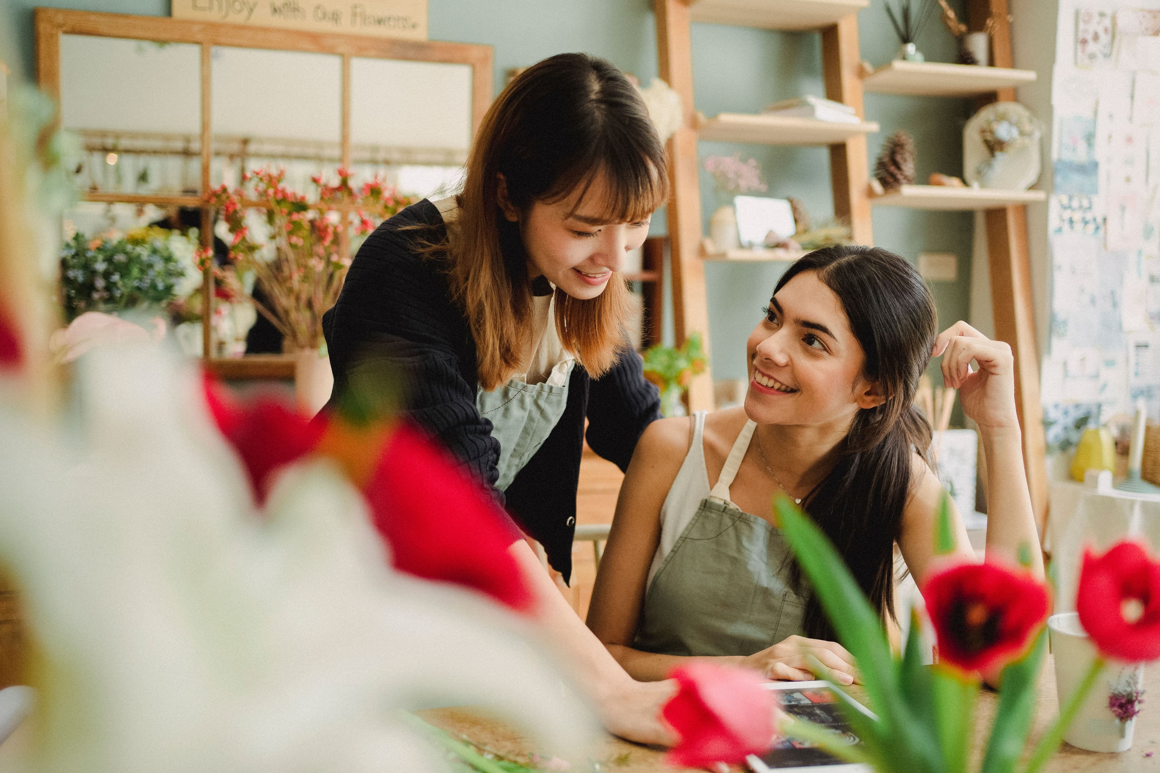 Dos floristas sonríen mientras trabajan juntas en su tienda de flores.